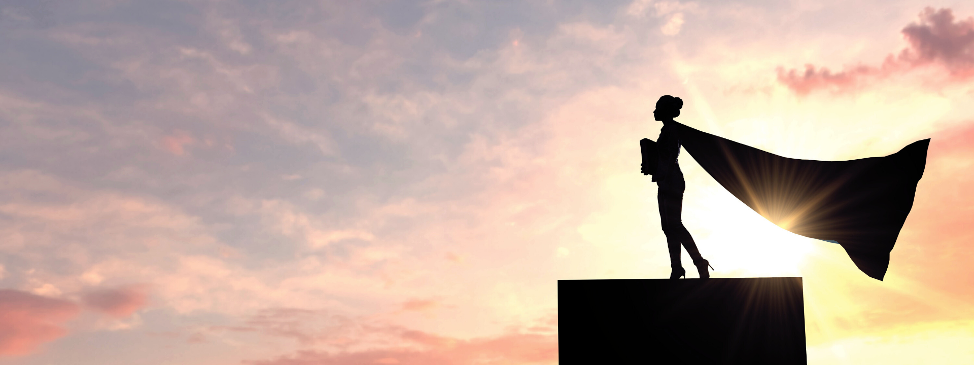 Silhouette of a superhero business woman wearing a cape against a bright sky